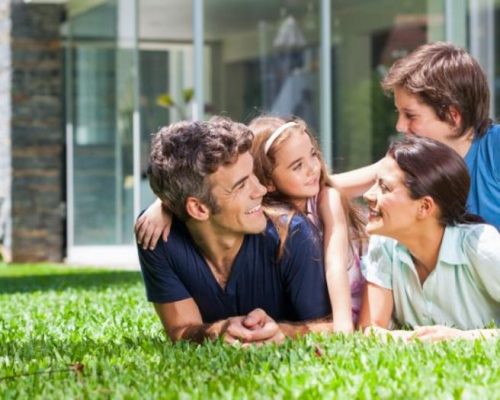 family of 4 lying on grass in backyard